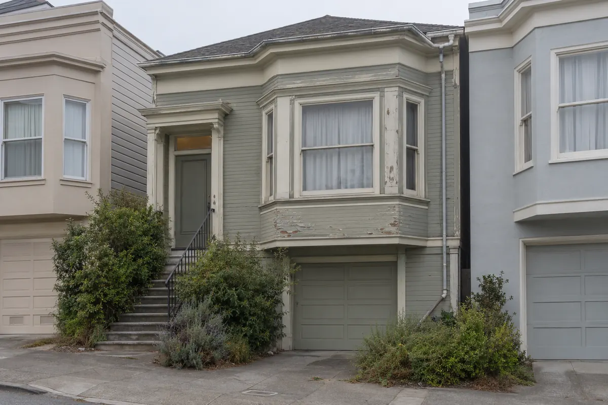 A house with peeling paint and worn roof shingles that needs repairs